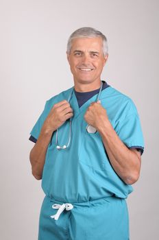 Smiling Middle Aged  Doctor in Scrubs holding stethoscope draped around his neck