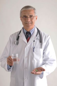 Middle Aged  Smiling Doctor in Labcoat with Pills and Glass of Water vertical format over light gray background