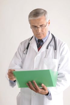 Middle Aged Doctor in Lab Coat Holding Folder with Patients Chart vertical format over gray background