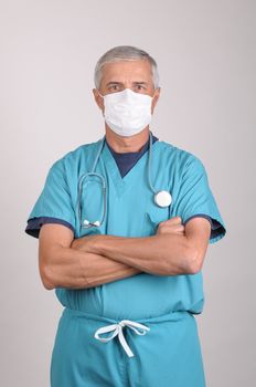 Middle Aged  Doctor in Scrubs with his arms folded wearing surgical mask