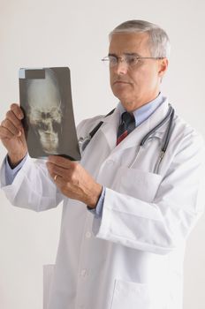 Middle Aged  Doctor in Lab Coat Looking at an X-Ray of a Skull