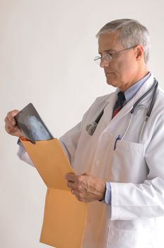 Middle Aged  Doctor in Lab Coat Removing an X-Ray from a large envelope