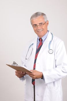 Portrait of a Middle Aged  Male Doctor in Lab Coat with Stethoscope and Clip Board, Vertical Composition on Gray Background