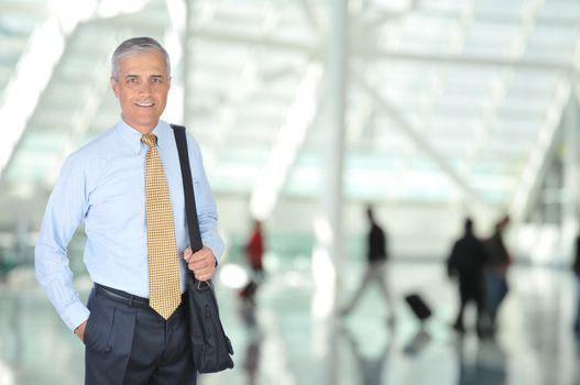 Middle aged Business Traveler in Airport Concourse with blurred travelers in background