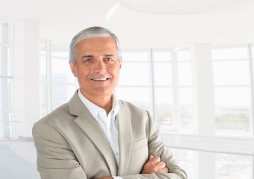 Closeup of a casual businessman in a modern office with his arms folded. Horizontal Format.