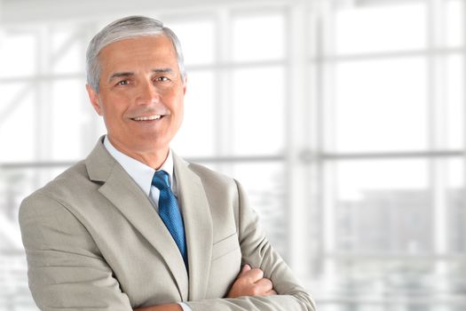 Closeup of a senior businessman with his arms folded in an office interior. Horizontal format with copy space.