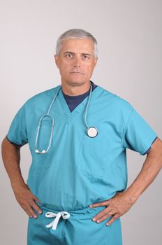 Serious Middle Aged  Doctor in Scrubs with Hands on Hips vertical on gray background
