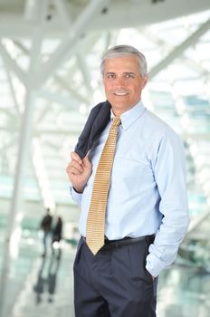 Smiling Middle aged Businessman Standing with Jacket Over Shoulder in Airport Concourse