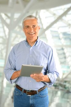 Closeup of a casual businessman in a modern factory holding a tablet computer. Vertical Format.