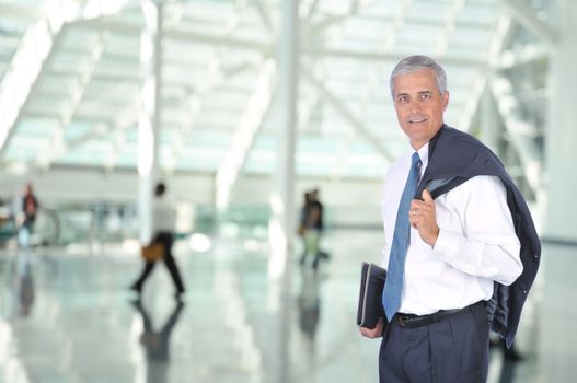 Middle aged Business Traveler in Airport Concourse with blurred travelers in background