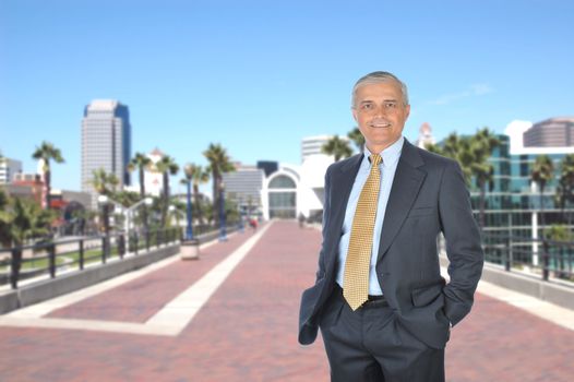 Middle aged Businessman standing on walkway with out of focus city skyline in background