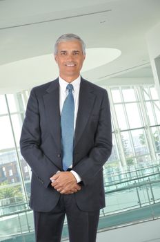 Standing Middle aged Businessman with hands in front in office setting