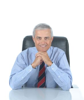 Smiling middle aged businessman seated at desk with reflection. Square format isolated over white.