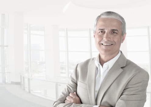 Casual businessman in a modern office with his arms folded. Horizontal format in high key. 