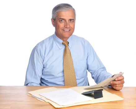 Smiling Businessman Seated at Desk with Newspaper and calculator isolated over white