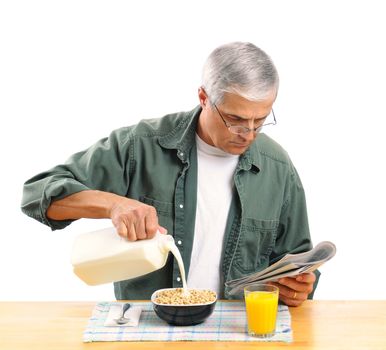 Casually dressed middle aged man pouring milk into his breakfast cereal bowl while reading the morning newspaper. Square format isolated over white.