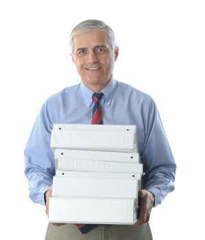 Smiling middle aged businessman carrying a stack of three ring binders isolated on white.