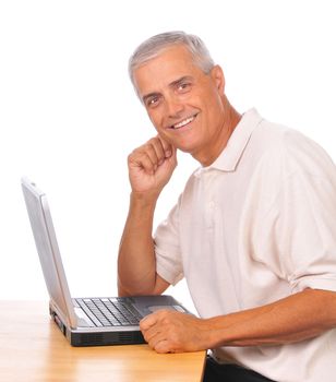 Smiling Mature Businessman Seated at Computer seen from the side isolated on white