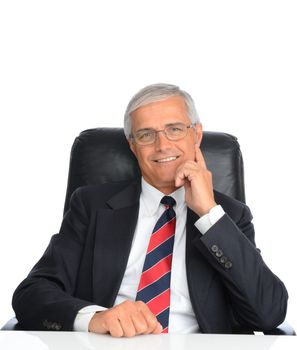 Portrait of a seated mature businessman with his hand next to his face. Man is smiling and wearing eyeglasses, over a white background.