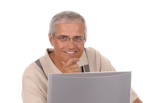 Casually dressed man sitting behind a computer monitor with his chin in his hand isolated on white background