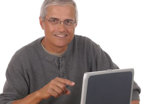 Middle aged man sitting and pointing at laptop computer. Man is smiling and casually dressed looking at camera. Horizontal format isolated on white.