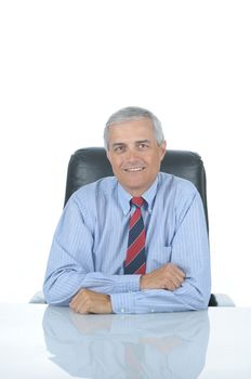 Smiling Middle aged businessman sitting at his desk isolated over white with reflection in desk top