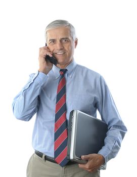 Smiling middle aged businessman talking on a cell phone, and holding a laptop computer under his other arm. Vertical format isolated on white. 