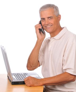 Businessman with Cell Phone Seated at Computer looking towards camera isolated on white
