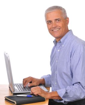 Smiling Mature Businessman Seated at Computer seen from the side isolated on white
