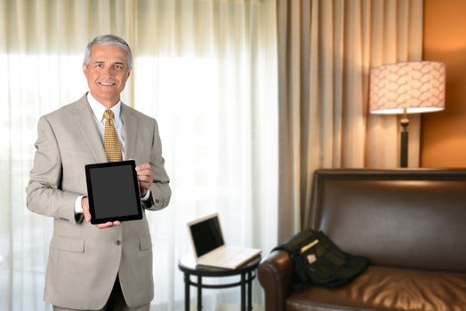 Businessman in hotel room with tablet computer. Business travel concept.