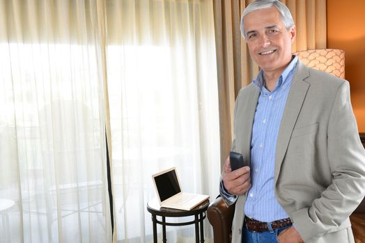 Business Travel Concept: Casual mature businessman in his hotel room. 