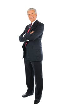 Smiling middle aged businessman in a suit and tie standing with his arms folded. Full length over a white background.