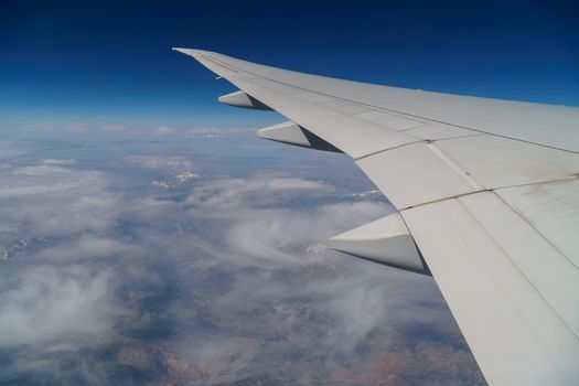 Flying and traveling, view from airplane window on the wing on a cloudy day. Wing of an airplane flying above the morning clouds.