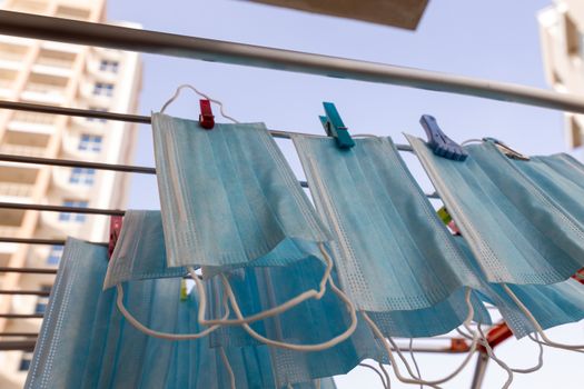 Blue disposable surgical mask washed and hanging on a drying rack. Concept of shortage of personal protection equipment (PPE). Concept of re usability and recycling during crisis times.