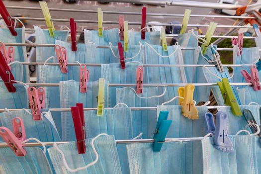 Blue disposable surgical mask washed and hanging on a drying rack. Concept of shortage of personal protection equipment (PPE). Concept of re usability and recycling during crisis times.