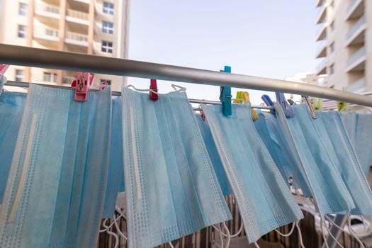 Blue disposable surgical mask washed and hanging on a drying rack. Concept of shortage of personal protection equipment (PPE). Concept of re usability and recycling during crisis times.