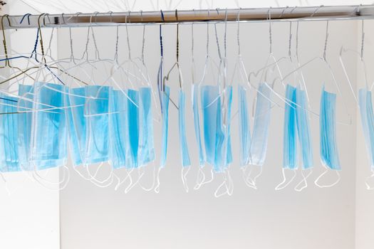 Disposable surgical masks hanging on hangers in a wardrobe closet. Concept of new normal. Concept of waring a mask becoming e new habit. Concept of adaptation during crisis and pandemic due to Covid.