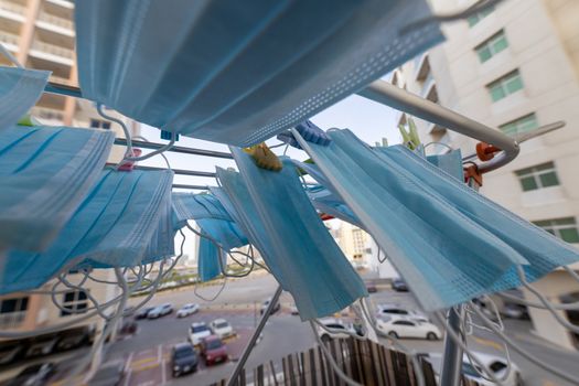 Blue disposable surgical mask washed and hanging on a drying rack. Concept of shortage of personal protection equipment (PPE). Concept of re usability and recycling during crisis times.