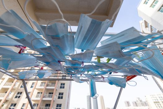 Blue disposable surgical mask washed and hanging on a drying rack. Concept of shortage of personal protection equipment (PPE). Concept of re usability and recycling during crisis times.