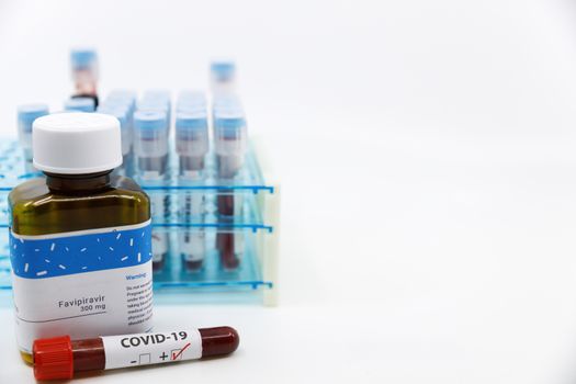 Dubai-UAE-Circa 2020:Coronavirus positive test in front of medicine.Concept of Favipiravir medicine with blood tests tubes on the background.Cure for coronavirus,COVID-19 treatment..