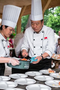 Sibiu City, Romania - 23 June 2019. Chinese cook arranges food on plates at the premiere of Lantern Festival from Astra museum in the Sibiu International Theatre Festival from Sibiu, Romania