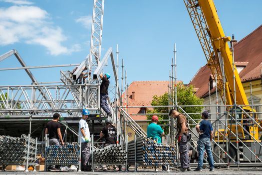 Sibiu, Romania - May 03, 2019. Construction workers working on scaffolding with crane