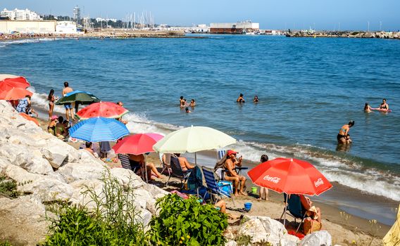 Marbella, Spain - June 27, 2018. Holidaymakers sunbathing on beach, Marbella city and resort area, province of Malaga, Andalucia region, Spain, Western Europe.