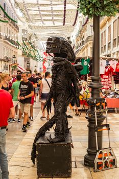 Malaga, Spain - August 12, 2018. Human statue of a Alien performs on the Marques de Larios pedestrian, in the historic center of Malaga, Spain