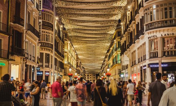 Malaga, Spain - June 22, 2018. People in motion on the Marques de Larios pedestrian street at night, Malaga city center, Spain.