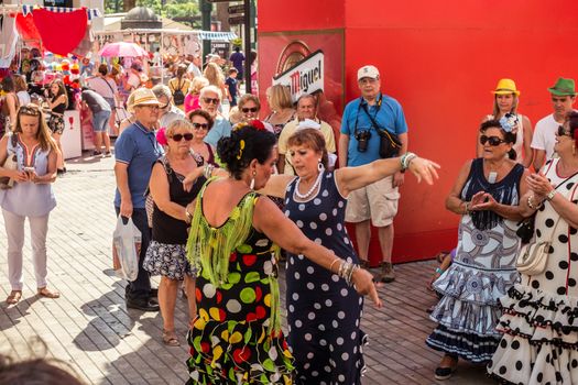 Malaga, Spain - August 18, 2018. People having fun on the street at the Feria de Malaga, an annual event that takes place in mid-August and is one of the largest fiestas in Spain