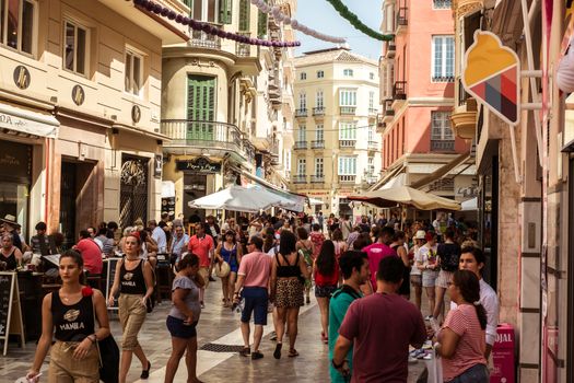 Malaga, Spain - August 12, 2018. People walking on the Old street around the historic center at the Feria de Malaga, an annual event that takes place in mid-August and is one of the largest fiestas in Spain