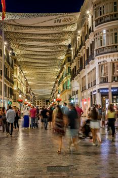 Malaga, Spain - June 22, 2018. People in motion on the Marques de Larios pedestrian street at night, Malaga city center, Spain.