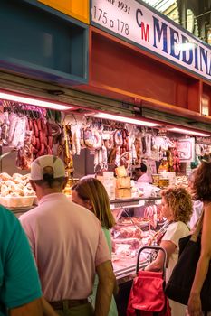 Malaga, Spain - August 04, 2018. Spanish prosciutto or jamon iberico and other Spanish specialities at the market of Ataranzanas Central Market, Malaga, Spain