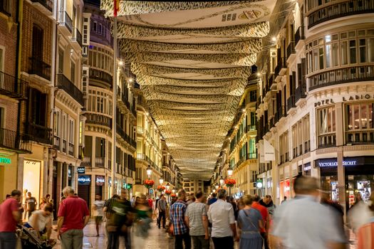 Malaga, Spain - June 22, 2018. People in motion on the Marques de Larios pedestrian street at night, Malaga city center, Spain.